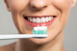 Tannbørste med tannkrem foran smilende munn