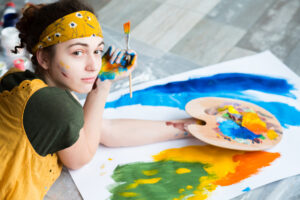 Ungdom maler med farger på palett