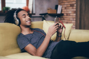Ung mann slapper av i sofaen og hører på musikk