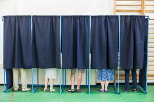 Fem personer i valgavlukket bak lukkede gardiner